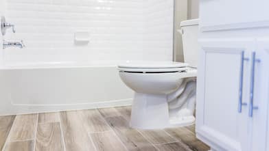 white bathroom toilet with caulking around rim       